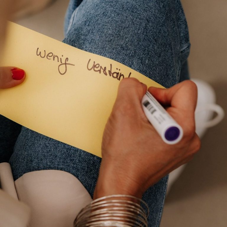 Eine Person schreibt mit einem Stift auf einen Zettel "wenig Verständnis".